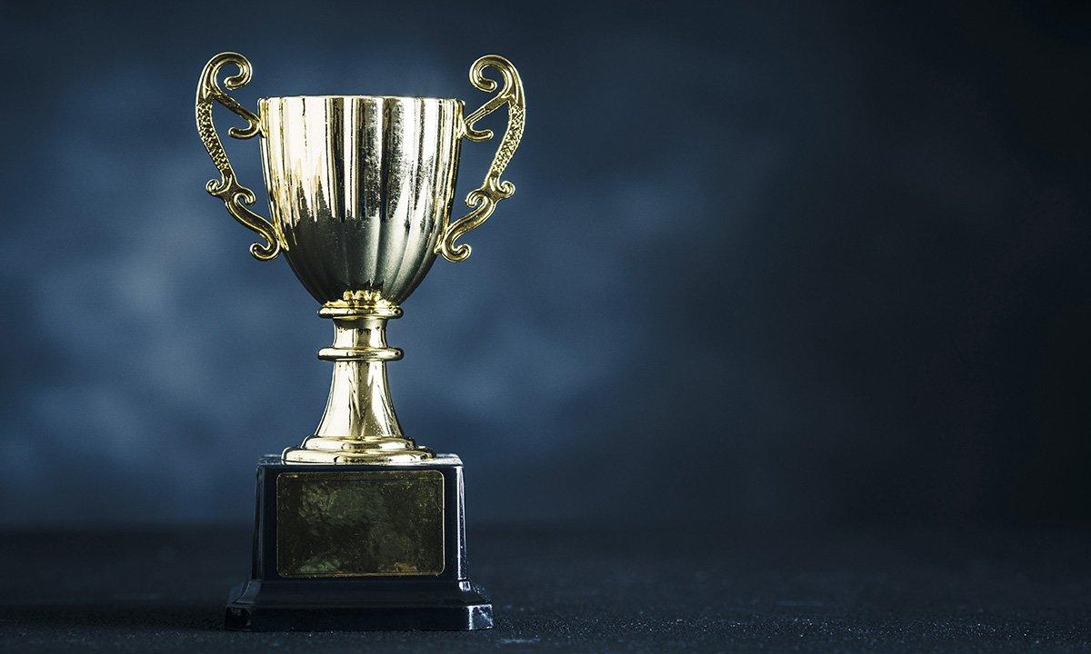 Silver trophy against blue backdrop. 